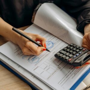 An accountant using a calculator and signing paperwork, showcasing financial analysis.